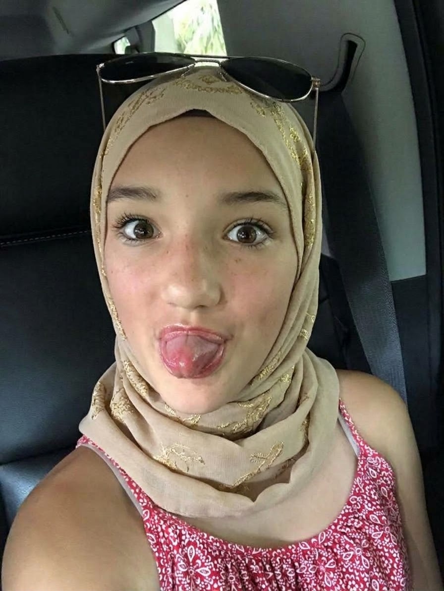 Portrait with a beige headscarf and pink top.