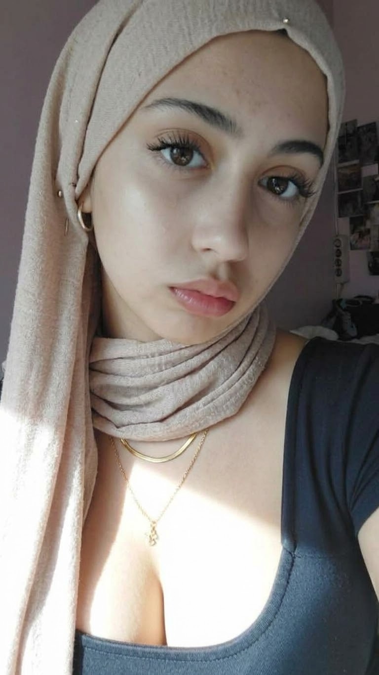 Portrait with a beige headscarf and black top.