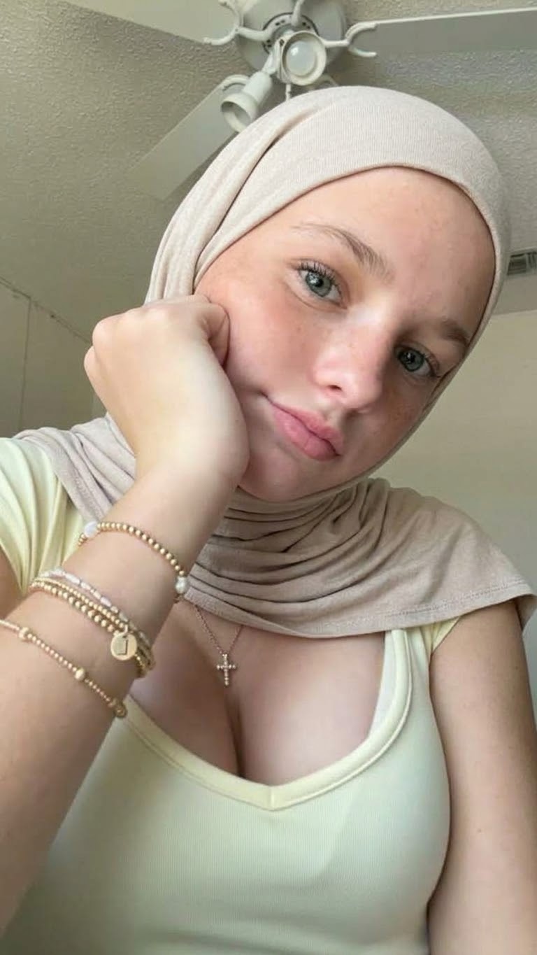 Portrait with a beige headscarf and green top.
