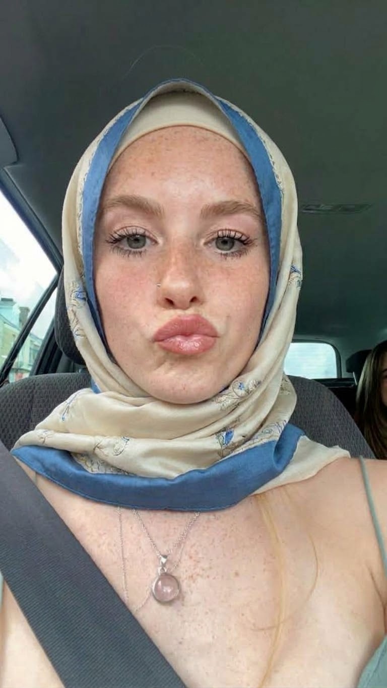 Portrait with a blue headscarf and white top.
