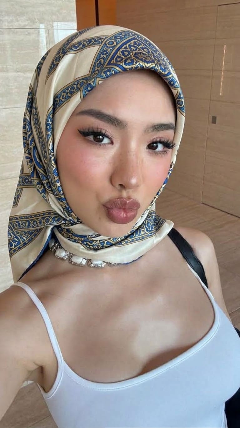 Portrait with a patterned headscarf and white top.