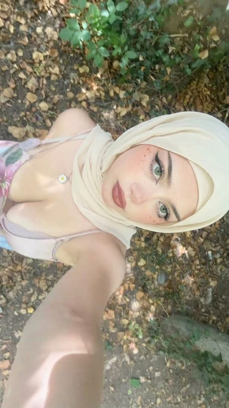 Portrait with a white headscarf and white top.