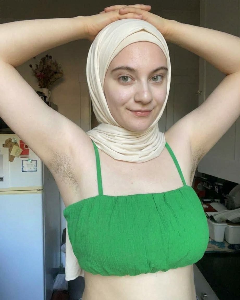 Portrait with a white headscarf and green top.