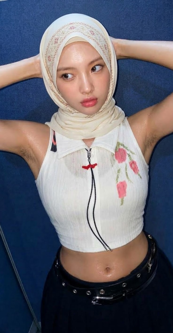 Portrait with a white headscarf and white floral top.