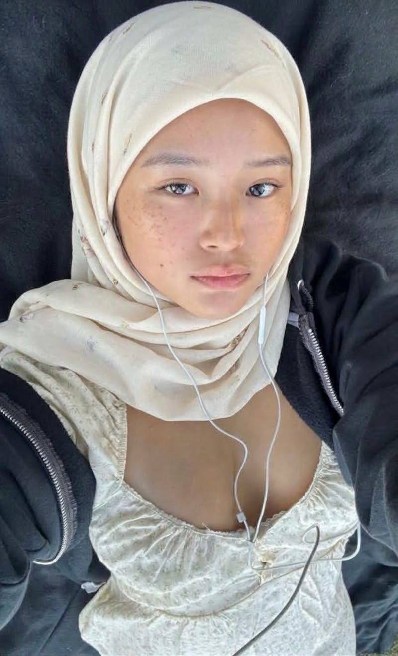 Portrait with a white headscarf and white top.